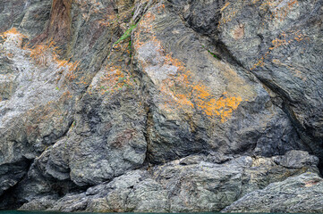 Interesting geologic feature in rock layers with colorful lichen, patterns and texture in nature, as a nature background
