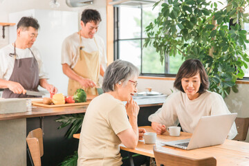Fototapeta premium 料理をする男性とパソコンを見ながら話す女性（二世帯住宅・三世代家族・シニア・夫婦） 