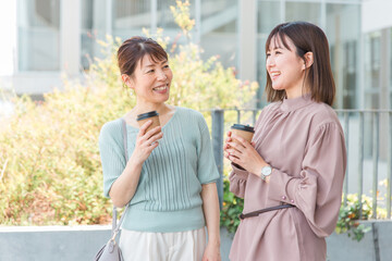 コーヒーを飲みながら会話する笑顔のアジア人ビジネスウーマン・女性
