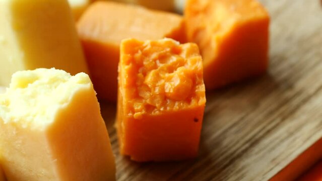 Cheese cubes green, yellow and red color on chopping board 