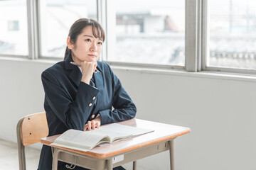 学校の教室で数学の教科書・参考書を見て悩みながら勉強する女子高校生・中学生の生徒（困る・難しい）
