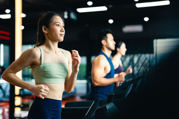 Fototapeta na wymiar Fit young woman and man running on a treadmill during a workout class at fitness gym
