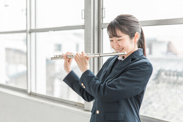教室でフルートの練習をする吹奏楽部のアジア人女子高生  © buritora