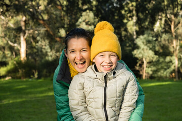  Lifestyle portrait of laughing mother and boy taken outdoors. Motherhood and childhood. Connection between mother and child.