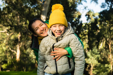 Woman hugging a boy in yellow hat from the back. Lifestyle portrait. Motherhood and childhood. Connection between mother and child.