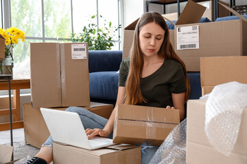 Young woman with parcel using laptop at home