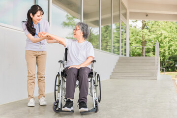 Fototapeta na wymiar 病院・介護施設で腕・肘のリハビリする車椅子に乗る高齢者と介護士（理学療法士・看護師） 