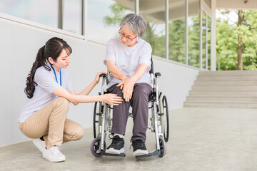 Fototapeta na wymiar 老人ホームで車椅子に乗りながらリハビリする高齢者と介護士（膝・膝痛） 