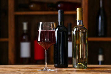 Bottles and glass of red wine on table in cellar
