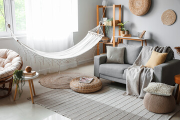Interior of light living room with hammock and grey sofa