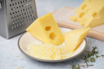 Plate and board with pieces of Swiss cheese on white table