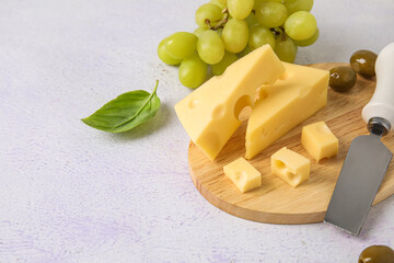 Wooden board with tasty Swiss cheese on light background