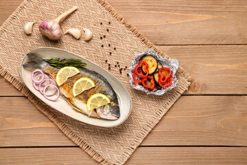 Plate with tasty grilled dorado fish on wooden background