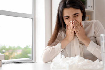 Sick woman with runny nose in office - obrazy, fototapety, plakaty