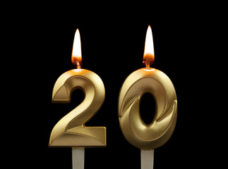 Burning gold birthday candles isolated on black background. Number 20.