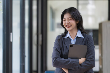 Fototapeta na wymiar Beautiful Asian businesswoman standing and holding a digital tablet.