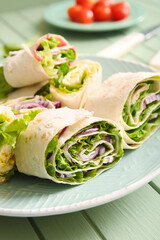 Plate of tasty lavash rolls with onion and greens on table