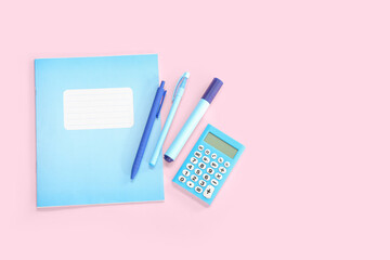 Notebook with different stationery on pink background