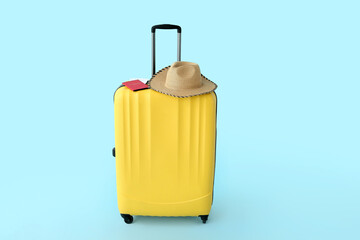 Suitcase with wicker hat, red passport and tickets on blue background. Travel concept