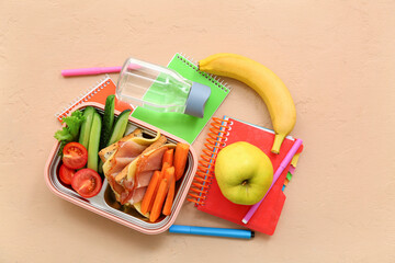 Stationery, drink and lunch box with tasty food on grunge orange background