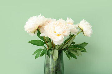Vase of white peonies on green background
