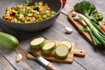Frying pan with different vegetables on grey wooden background