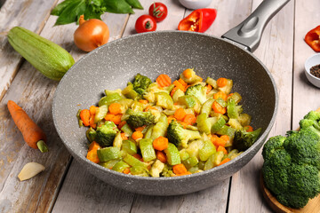Frying pan with different vegetables on grey wooden background