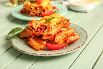 Plates of pasta with tomato sauce and cheese on green wooden background