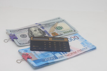 Dollars, calculator and paper clip on a white background.