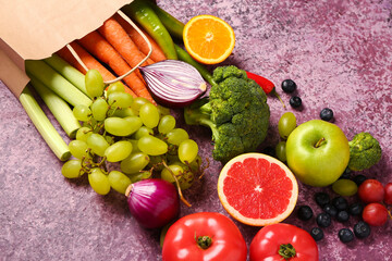 Paper bag with different fresh fruits and vegetables on purple background