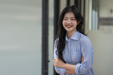 Beautiful Asian businesswoman standing with her arms crossed and looking at the camera smiling and laughing happily.