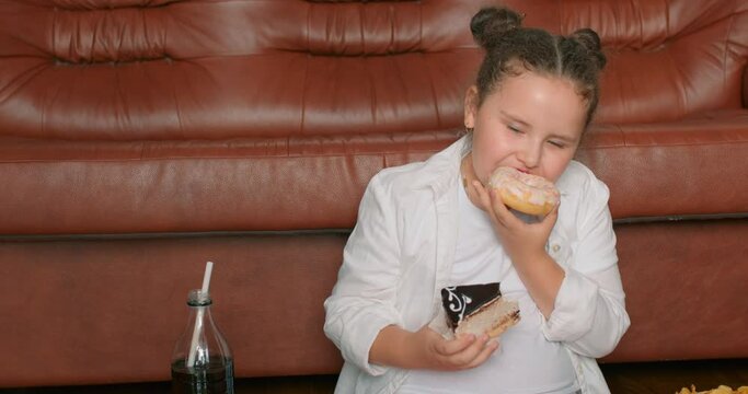 fat hungry little girl biting piece of cake, eating donut Sweet tooth. Self-control. Obesity, unhealthy eating, dieting. overweight child leads unhealthy lifestyle.