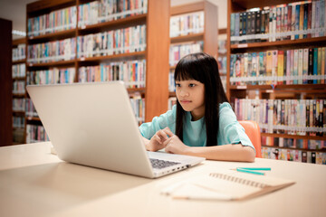 Little girl choosing book in public library room selecting literature for reading. girl chooses...