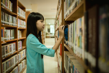 Little girl choosing book in public library room selecting literature for reading. girl chooses books on shelves learning from books is school education benefits of everyday reading concept.