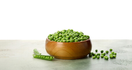 Bowl with fresh green peas on black table against white background