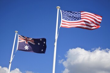 Flag of United States of America fly beside the flag of Australia against clear blue sky