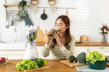 Portrait of beauty healthy asian woman making green vegetables detox cleanse and green fruit smoothie with blender.young girl drinking glass of smoothie, fiber, chlorophyll in kitchen.Diet, healthy