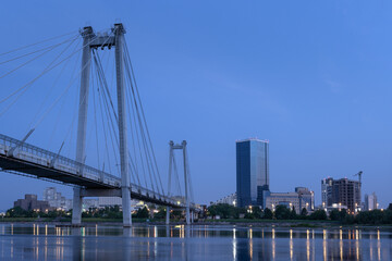 Panorama of the night city of Krasnoyarsk. View of the Vinogradovsky suspension bridge and the outlines of buildings in the morning, at night before dawn. lights of the Yenisei