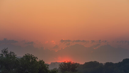 The red sun rises over the city. Dawn and orange sky copy space