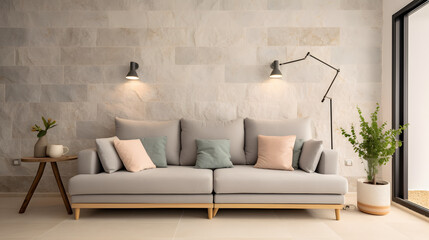 Fototapeta na wymiar Light grey living room sofa decorated with pillows, a lamp, a bag and a plant in front of a natural stone wall