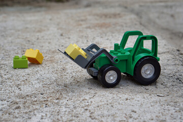 Grüner Spielzeug Traktor mit Spielsteinen auf der Schaufel von Duplo