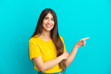 Young caucasian woman isolated on blue background pointing finger to the side