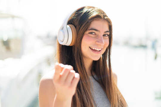 Young pretty caucasian woman listening music and pointing to the front
