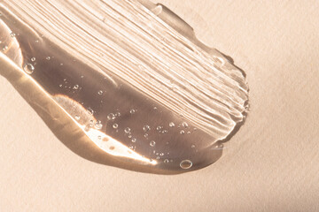 A sample of a cosmetic product on a beige background macro. Smear of hyaluronic gel, serum close-up.