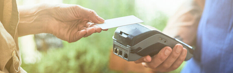 Woman paying contactless with card to male seller