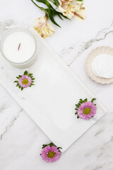 Fototapeta na wymiar Flatlay of Flowers, Candles, Skincare, Cotton Pads, Aesthetic Dishes and Trays on Marble Table