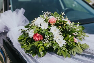 Colorful bouquet of fresh flowers arranged on the hood of a car on a wedding day