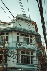 Majestic white and blue building near intertwining electric cables in Bangkok, Thailand