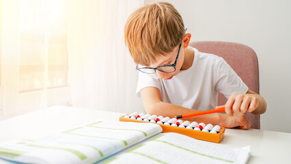 The boy is engaged in abacus, mental arithmetic for children - obrazy, fototapety, plakaty