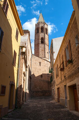 Fototapeta na wymiar Old street with church tower and stone houses in Alghero city on Sardinia island, Italy.